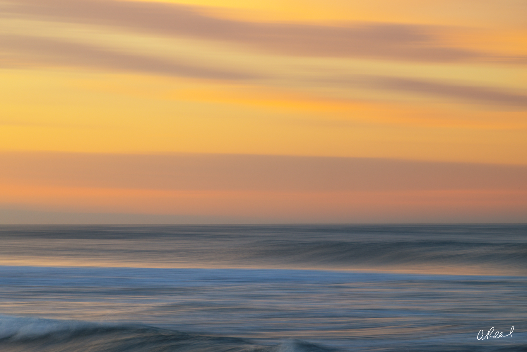 Breathe Abstract ocean photography print with soft blue waves beneath a glowing golden, peach and lavender sunset sky.