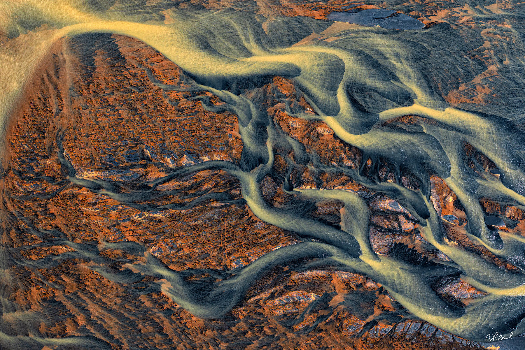 Texture In Time Aerial view of golden braided glacial rivers winding through blue-gray and rust-colored volcanic terrain in Iceland.
